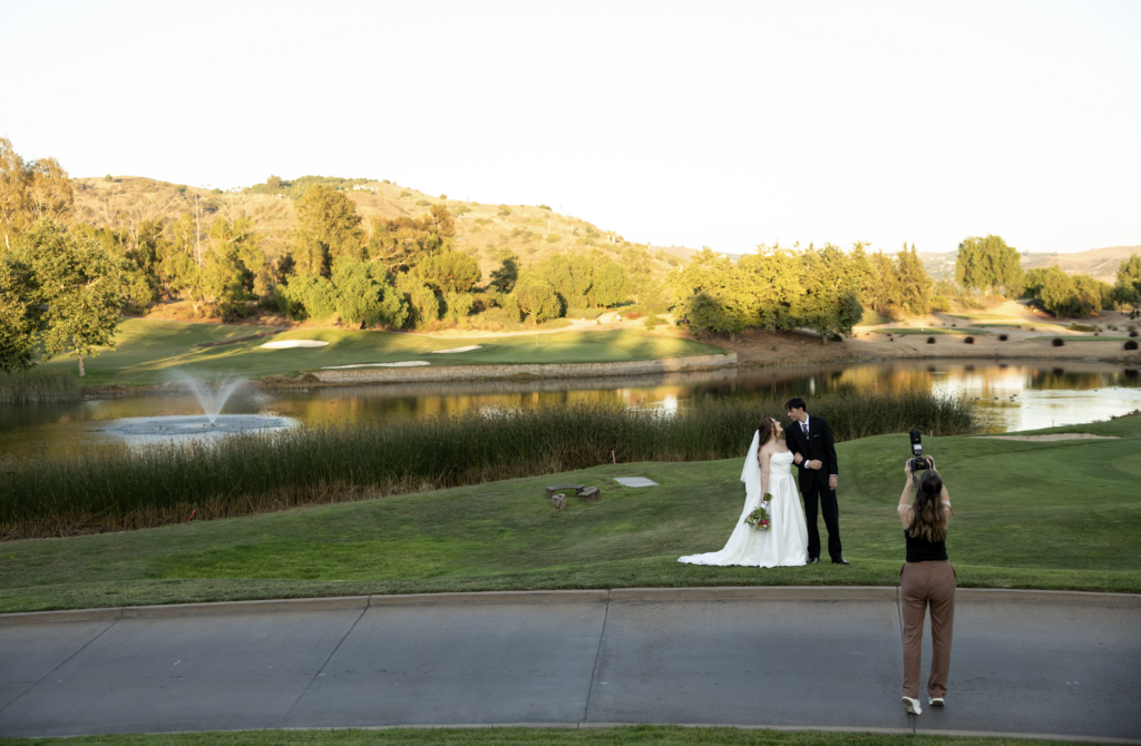 Candid photo of taking couple portraits at golf course San Diego wedding